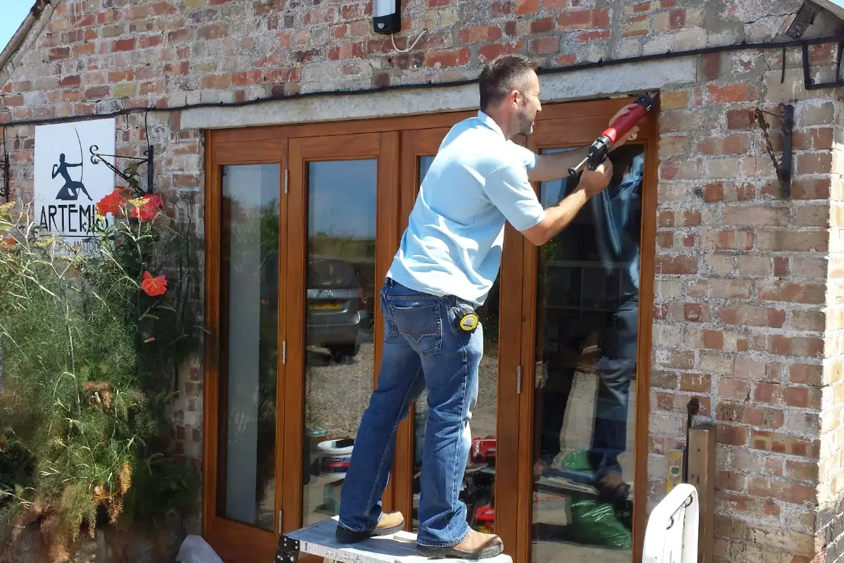 Builder fitting large glazed doors to a traditional brick property exterior