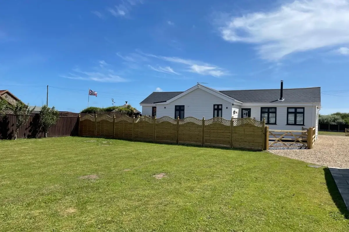 White countryside holiday lodge with fenced garden, lawn and gravel driveway